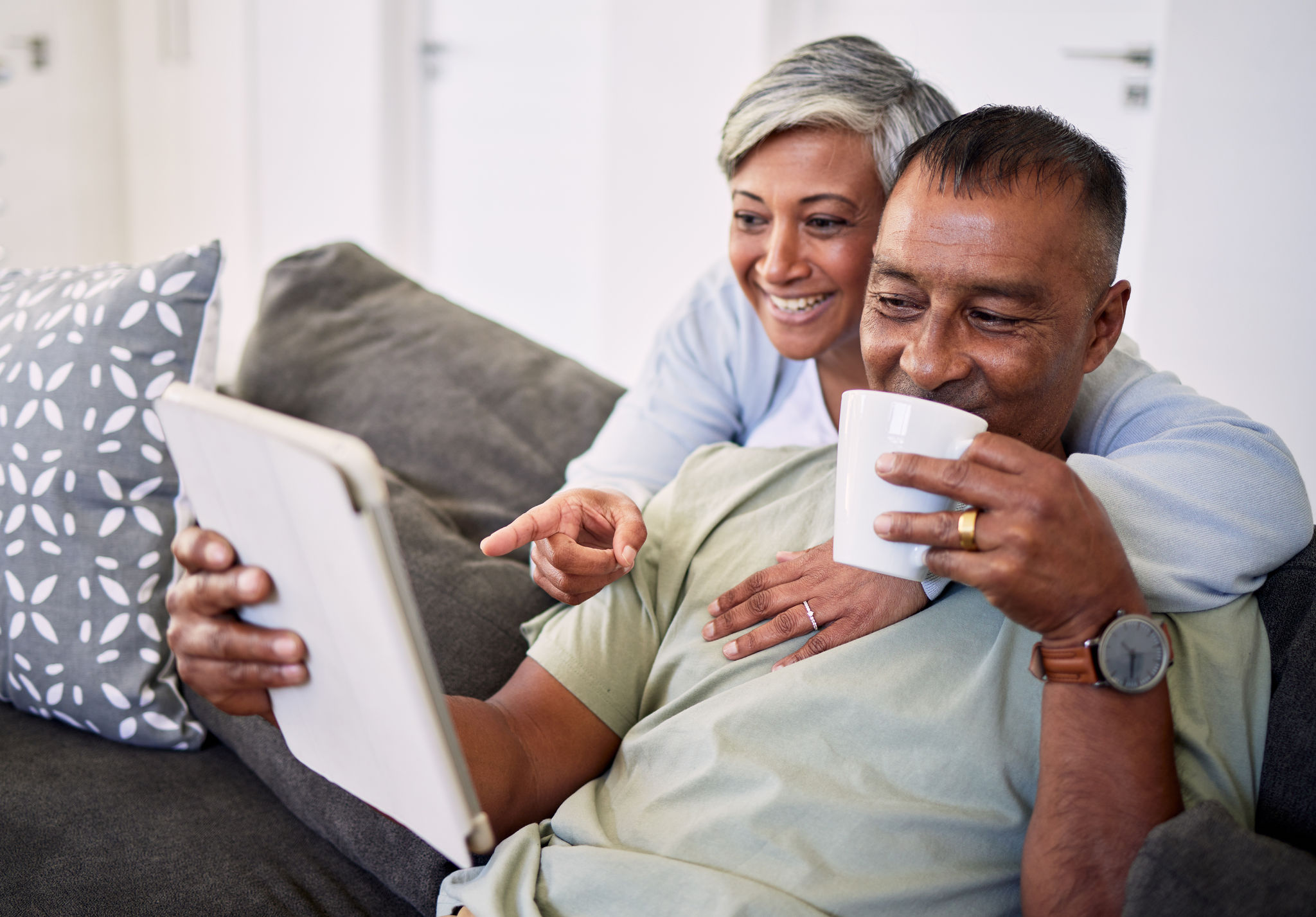 Home, tablet and happy senior couple on sofa, relax and check email, news article and point at online shopping choice. Website info, decision or elderly man, old woman or people smile in living room.