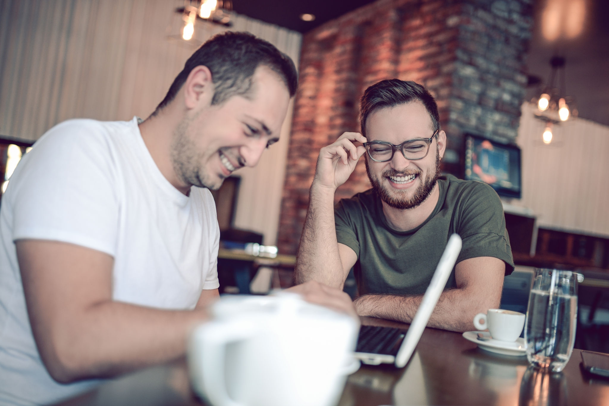 Two Smiling  Male Freelancers Drinking Coffee and Working In Cafe Restaurant