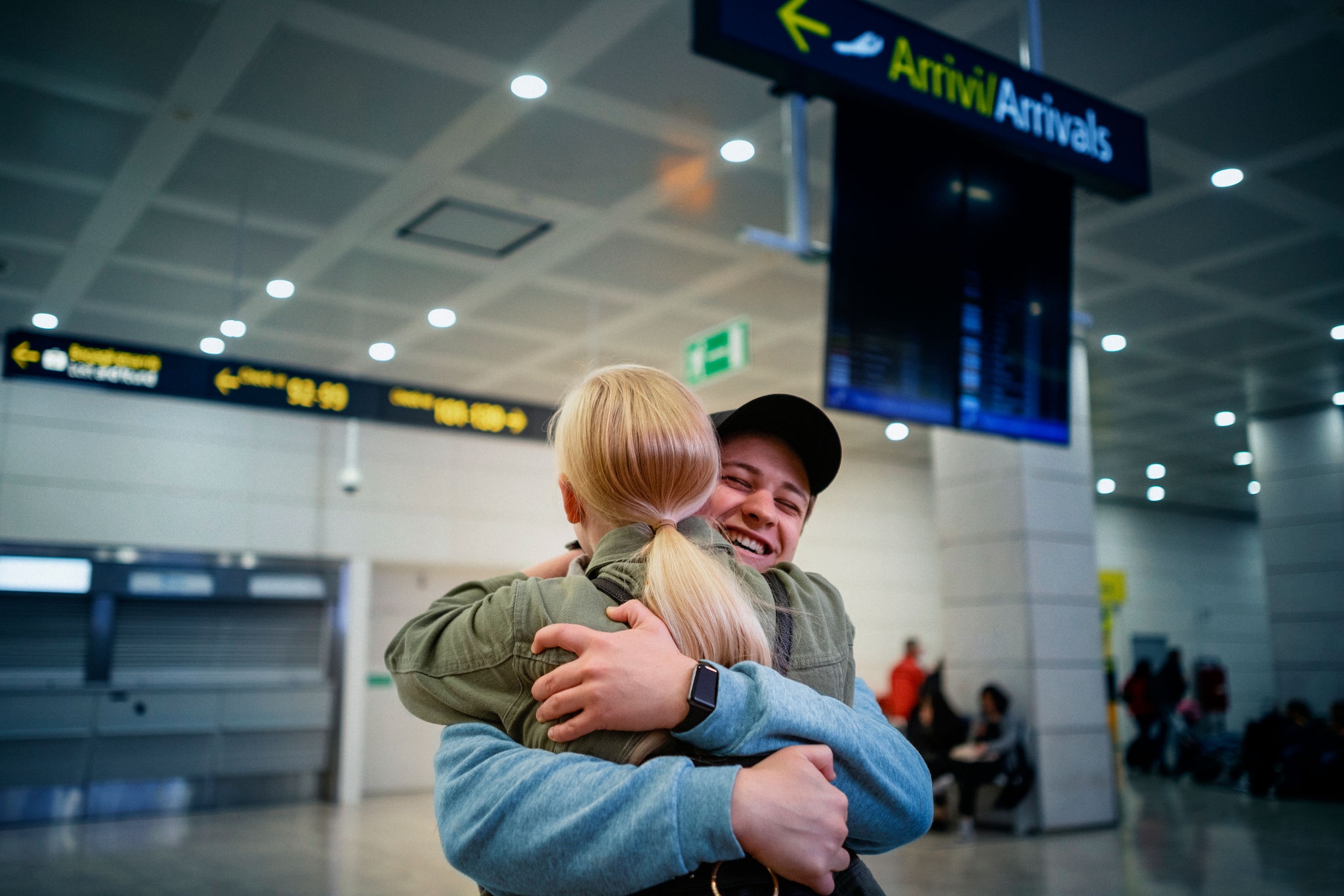 A young woman is hugging her boyfriend upon arrival in the airport