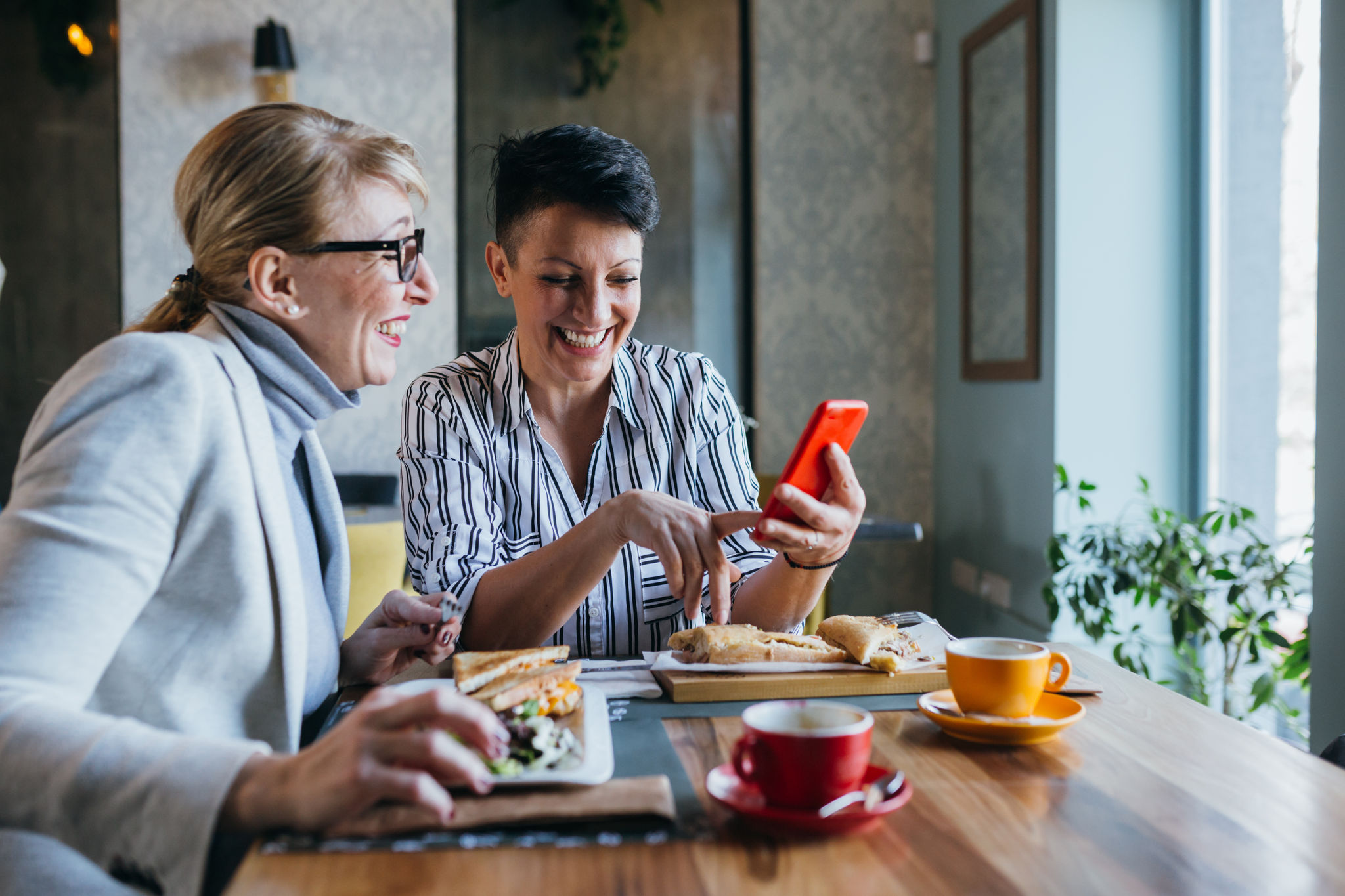 women friends eating in restaurant, using mobile phone
